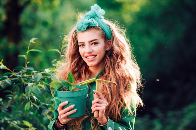 Ragazza felice con i capelli lunghi in possesso di un vaso di fiori Piantare e fiorire concetto Bella ragazza in giardino primaverile