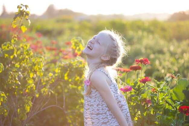 Ragazza felice con i fiori in giardino al tramonto