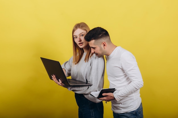 Ragazza felice con il ragazzo che guarda il laptop su sfondo giallo Studiano insieme Risolvi i problemi Concetto di lavoro di apprendimento