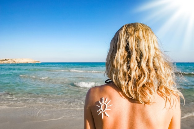 Ragazza felice con il sole sulla schiena in riva al mare nella natura