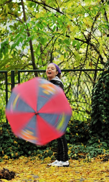 ragazza felice con l'ombrello all'aperto nel parco il giorno della pioggia della stagione autunnale