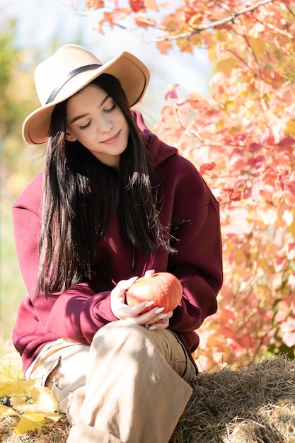 Ragazza felice con la zucca nel giardino d'autunno