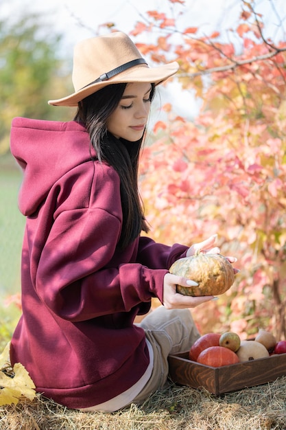 Ragazza felice con la zucca nel giardino d'autunno