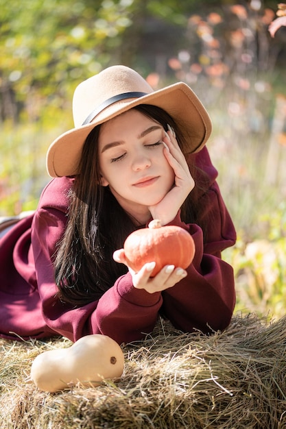 Ragazza felice con la zucca nel giardino d'autunno