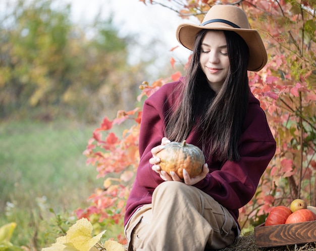 Ragazza felice con la zucca nel giardino d'autunno