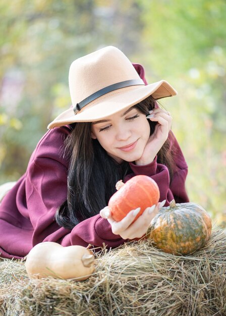 Ragazza felice con la zucca nel giardino d'autunno