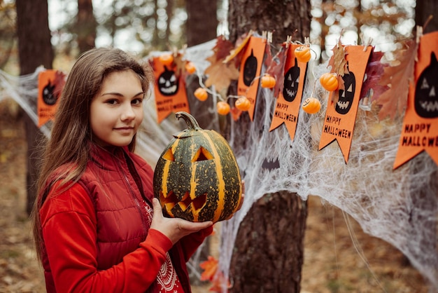 Ragazza felice con la zucca nelle sue mani all'aperto nel parco autunnale Concetto di Halloween