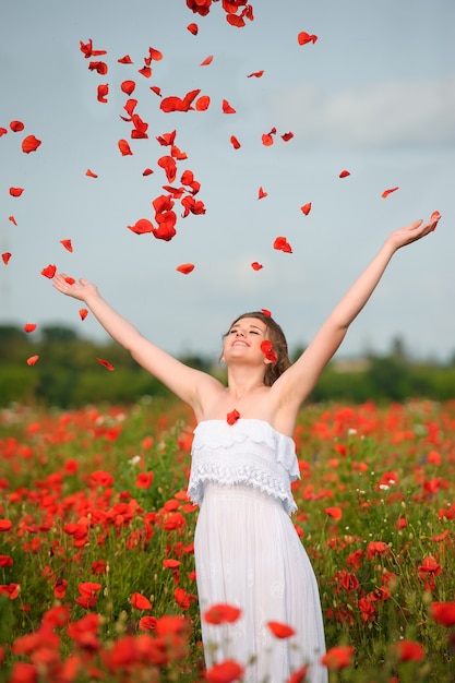 Ragazza felice con le braccia alzate nel campo verde dei fiori. Concetto di libertà e felicità.
