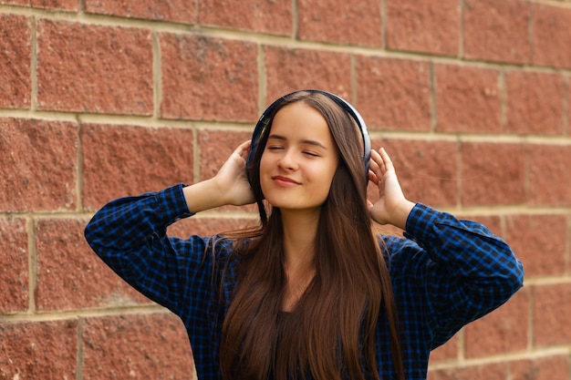 Ragazza felice con le cuffie per strada ascoltando musica sul suo smartphone