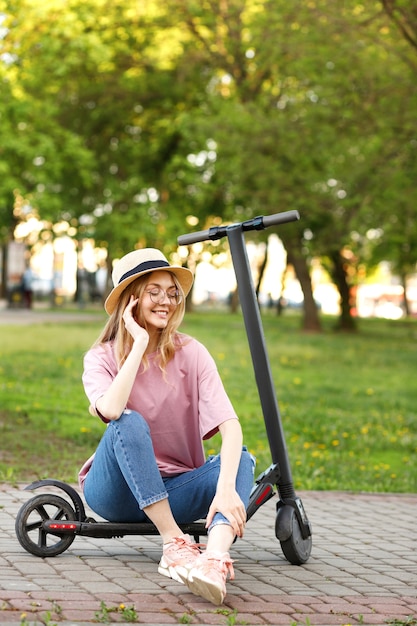 Ragazza felice con lo scooter nel parco in estate