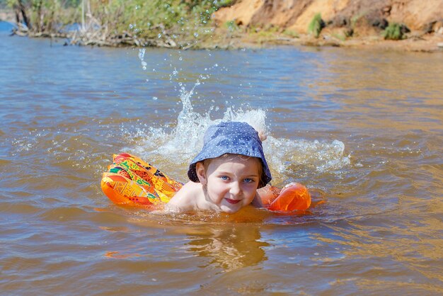 ragazza felice con un cappello gioca nell'acqua e schizza