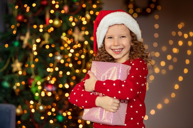 Ragazza felice del bambino che ride con il regalo di Natale a casa