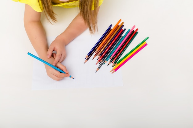 Ragazza felice del bambino che si trova sul pavimento e che disegna con le matite colorate, isolato, spazio per testo