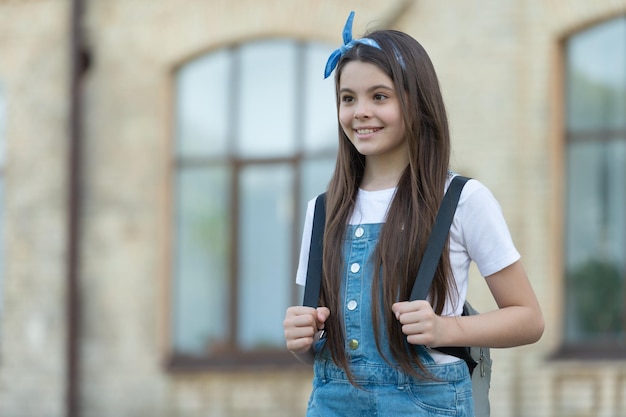 Ragazza felice del denim con lo spazio della copia all'aperto dello zaino