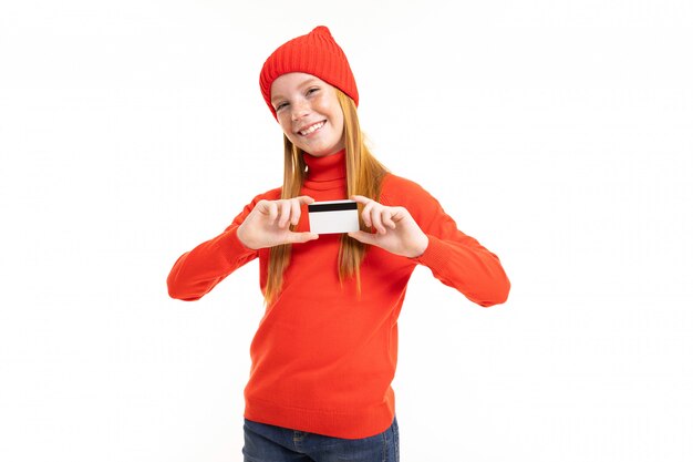 Ragazza felice dell'adolescente con capelli rossi, maglia con cappuccio rossa e cappello con la carta isolata su fondo bianco