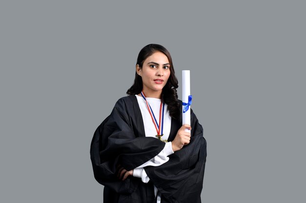 Ragazza felice dello studente laureato che tiene un modello pakistano indiano del diploma in mano