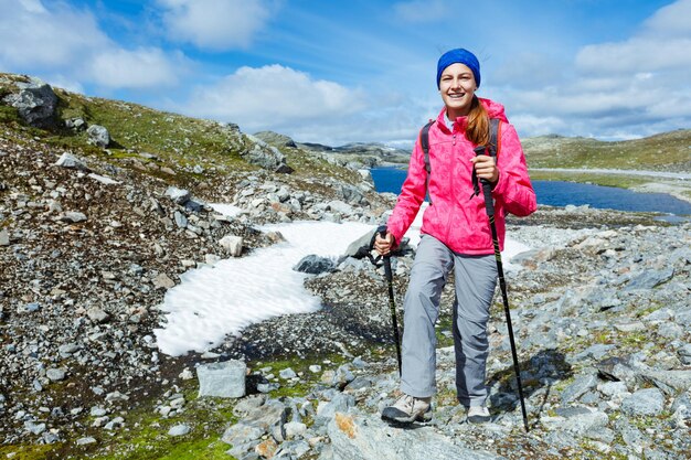 Ragazza felice di escursionismo con bastoncini da trekking in montagna. Norvegia