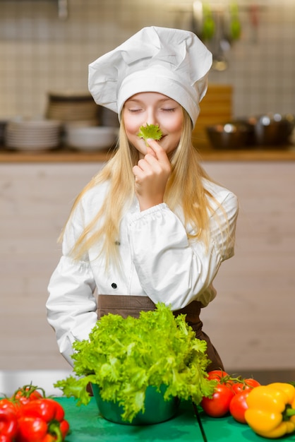 Ragazza felice divertente che cucina alla cucina del ristorante