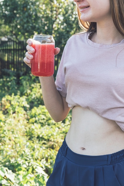 Ragazza felice e distogliere lo sguardo mentre si gusta un frullato sano e fresco