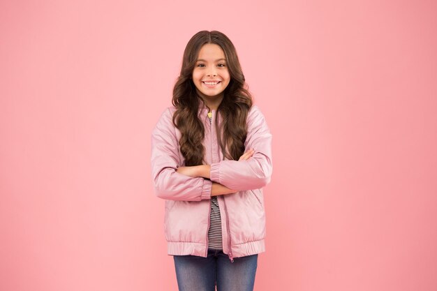 Ragazza felice in abbigliamento casual sfondo rosa Bambina in stile casual Guardaroba casual per la stagione autunnale o primaverile Tendenza e stile della moda Bambini essenziali per le attività all'aperto Il casual porta gioia