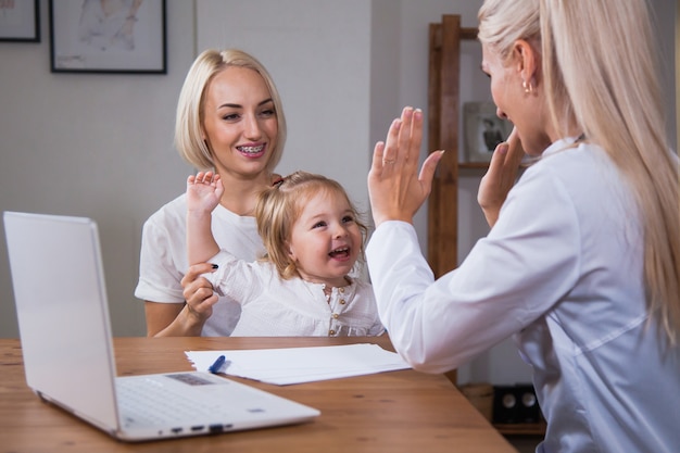 Ragazza felice in buona salute del bambino che dà il cinque al medico premuroso femminile. celebrare un buon risultato medico, pediatra con il concetto di fiducia di un buon rapporto paziente bambino