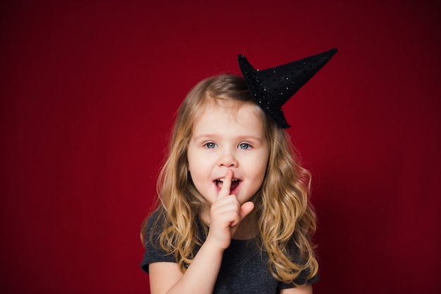 ragazza felice in cappello da strega su sfondo rosso