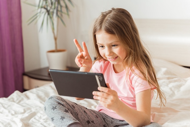 Ragazza felice in chat online a casa sul letto