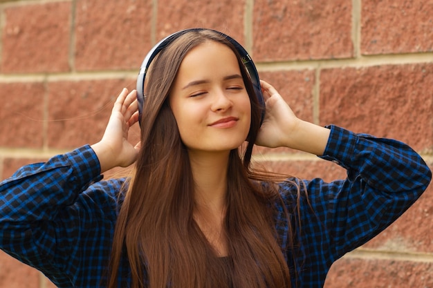 Ragazza felice in cuffia per strada ascoltando musica al telefono, cantando, ballando, sorridendo