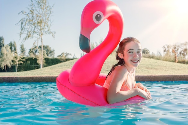 ragazza felice in piscina con ritratto galleggiante di fenicottero
