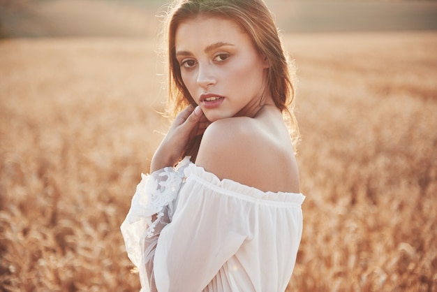 Ragazza felice in un campo di frumento sotto luce solare.