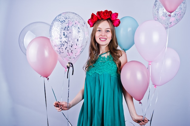 Ragazza felice in vestito e corona verdi dal turchese con gli aerostati colorati isolati su bianco. Festeggia il tema del compleanno.