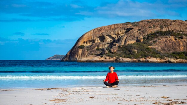 ragazza felice seduta e meditando sulla spiaggia della baia fortunata nell'australia occidentale giornata di sole in paradiso