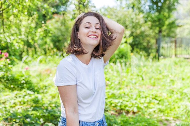 Ragazza felice sorridente all'aperto bella giovane donna brunete che riposa sul parco o giardino verde