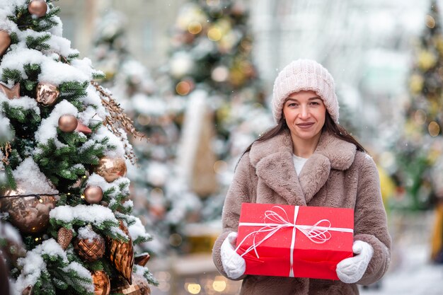 Ragazza felice vicino al ramo dell'abete in neve per il nuovo anno.