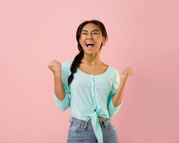 Ragazza felicissima che celebra la vittoria o il trionfo sfondo rosa