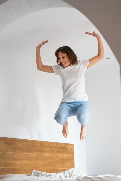 ragazza felicissima in pigiama che salta sul letto