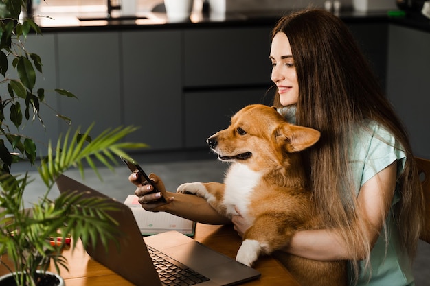 Ragazza freelance con laptop che fa selfie facendo selfie con il suo cane Corgi Ragazza fa una pausa al lavoro per fare selfie con il suo animale domestico Stile di vita del Welsh Corgi Pembroke pet