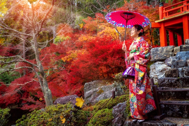 Ragazza giapponese in abito tradizionale kimono a piedi in un parco