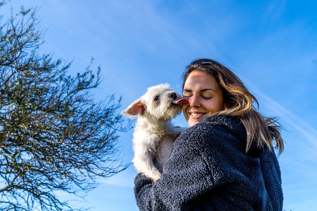 Ragazza gioca con il suo cane bianco in una giornata di sole