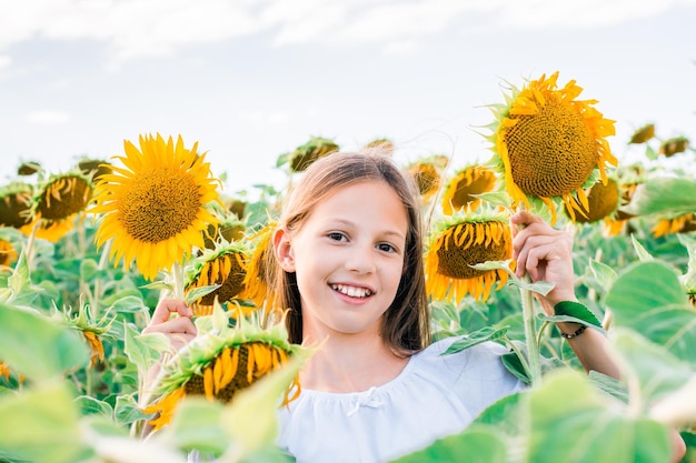 Ragazza gioiosa con girasoli nel campo al sole Turismo locale e libertà