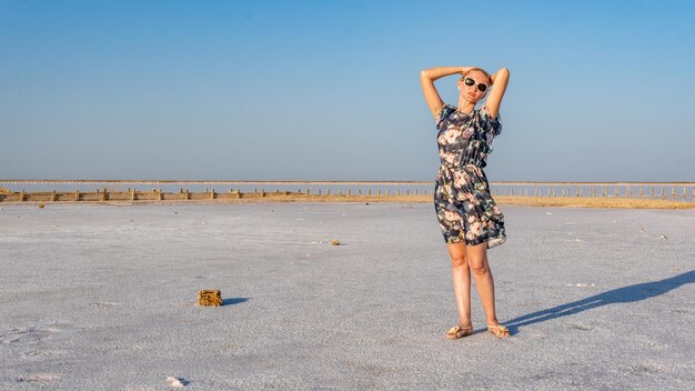 Ragazza gioiosa in un bel vestito giovane sullo sfondo di un lago bianco di sale al caldo