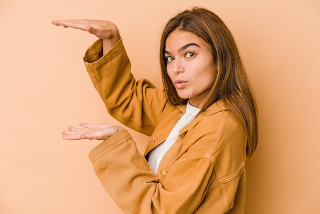 Ragazza giovane adolescente magra che tiene qualcosa con entrambe le mani, presentazione del prodotto