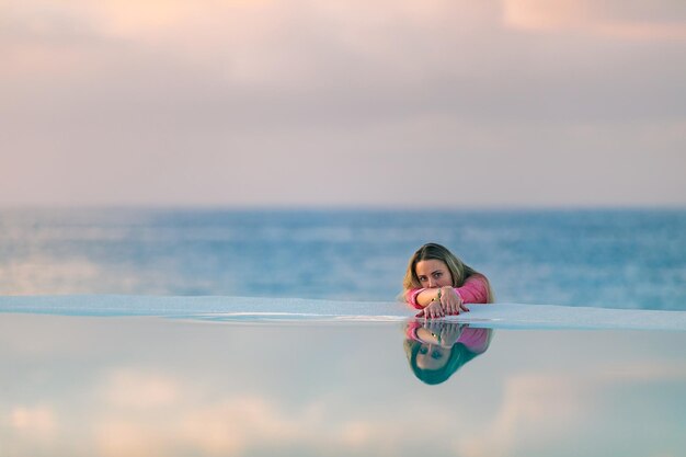Ragazza giovane all'alba vicino alla piscina calma e rilassata.
