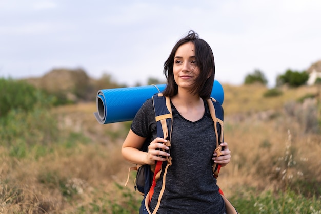 Ragazza giovane alpinista con un grande zaino all'aperto