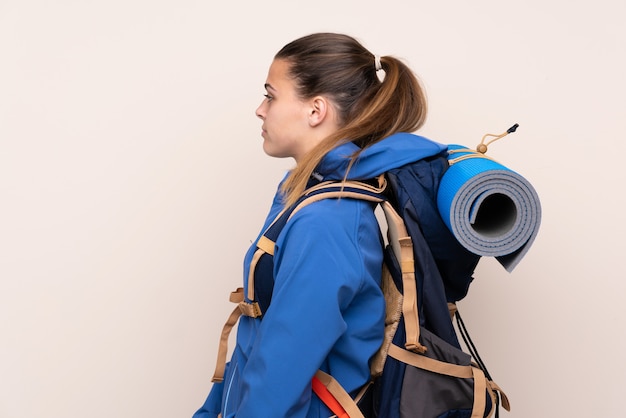 Ragazza giovane alpinista con un grande zaino che guarda al lato