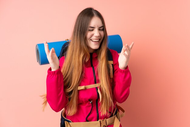 Ragazza giovane alpinista con un grande zaino isolato sulla risata rosa della parete