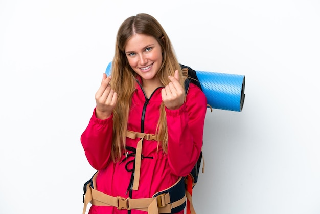 Ragazza giovane alpinista con un grande zaino sopra fondo bianco isolato che fa gesto di soldi