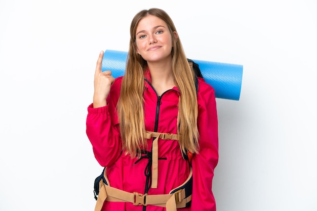 Ragazza giovane alpinista con un grande zaino su sfondo bianco isolato che punta con il dito indice una grande idea