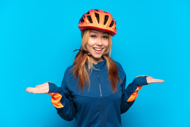 Ragazza giovane ciclista isolata su priorità bassa blu con l'espressione facciale scioccata