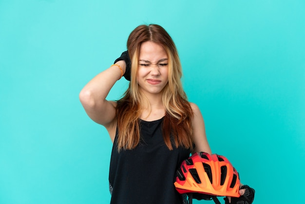 Ragazza giovane ciclista su sfondo blu isolato frustrata e che copre le orecchie